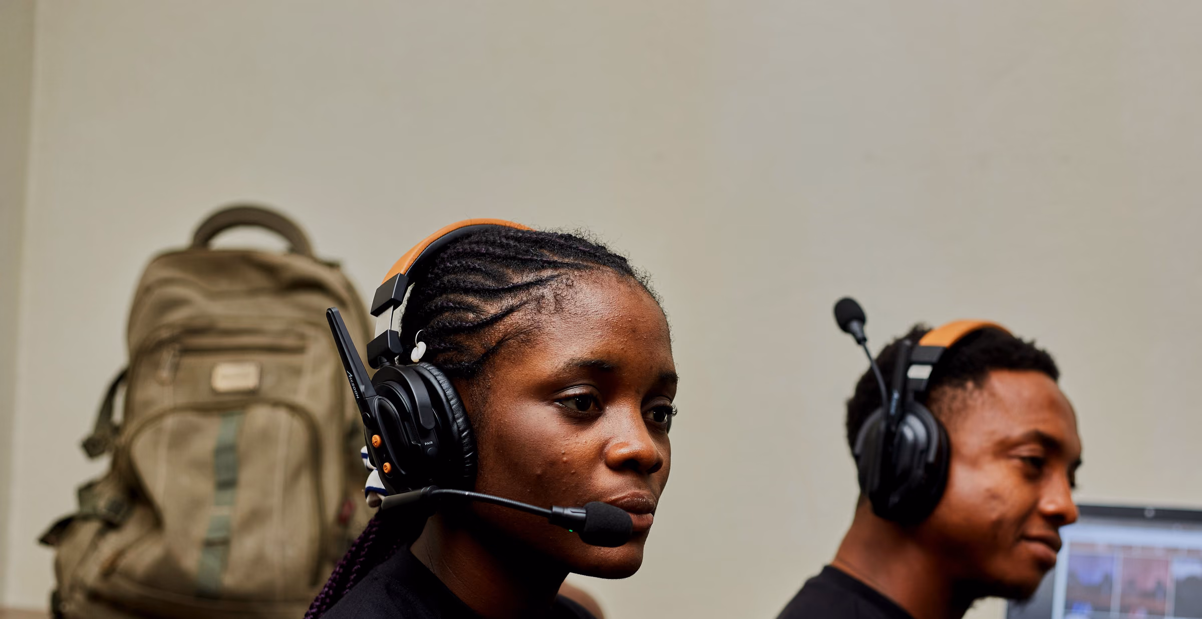 Two crew members in headsets at a desk, one with a boom mic, a switching laptop behind them