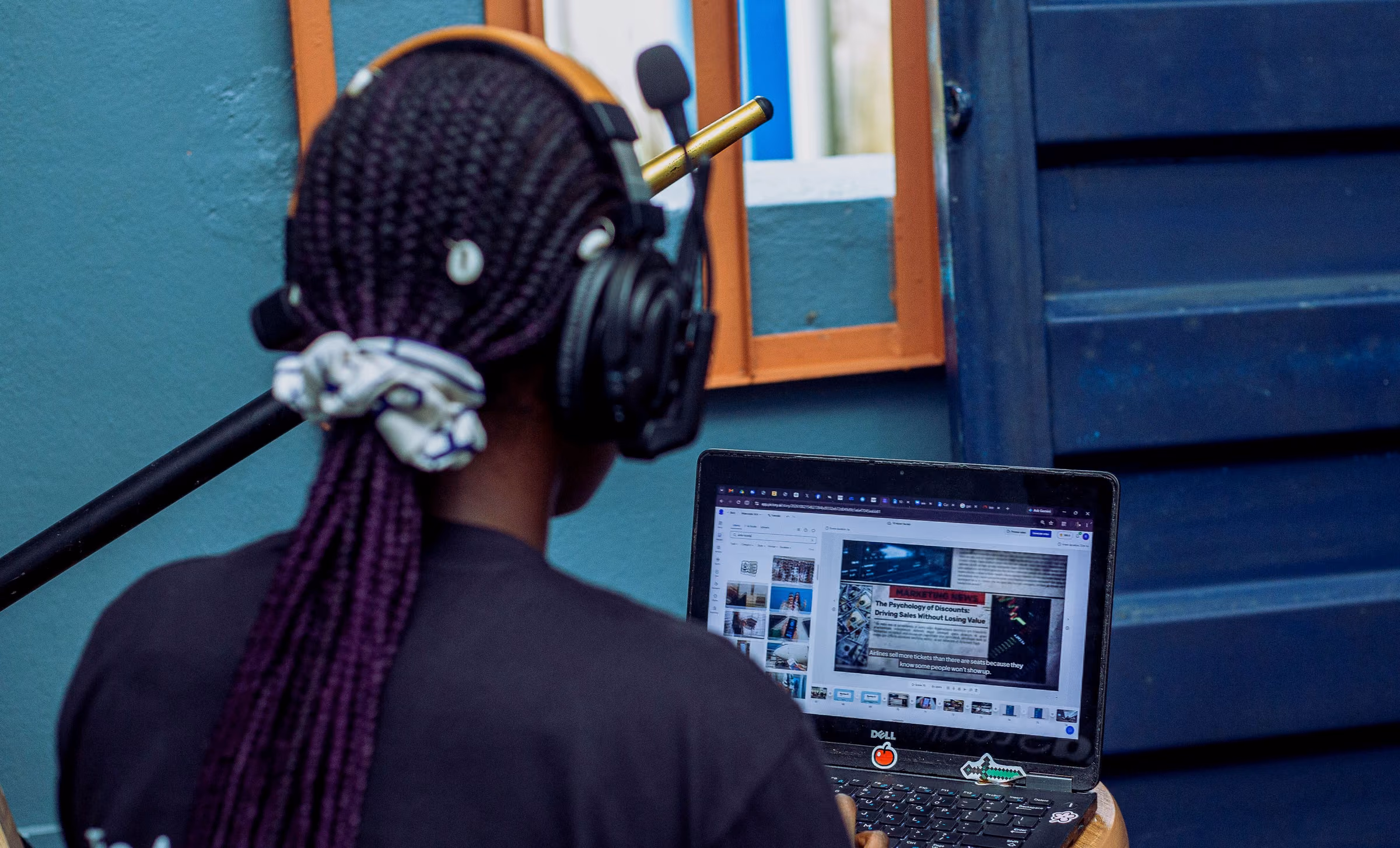 Operator seen from behind in a headset, working a laptop that shows the live production software