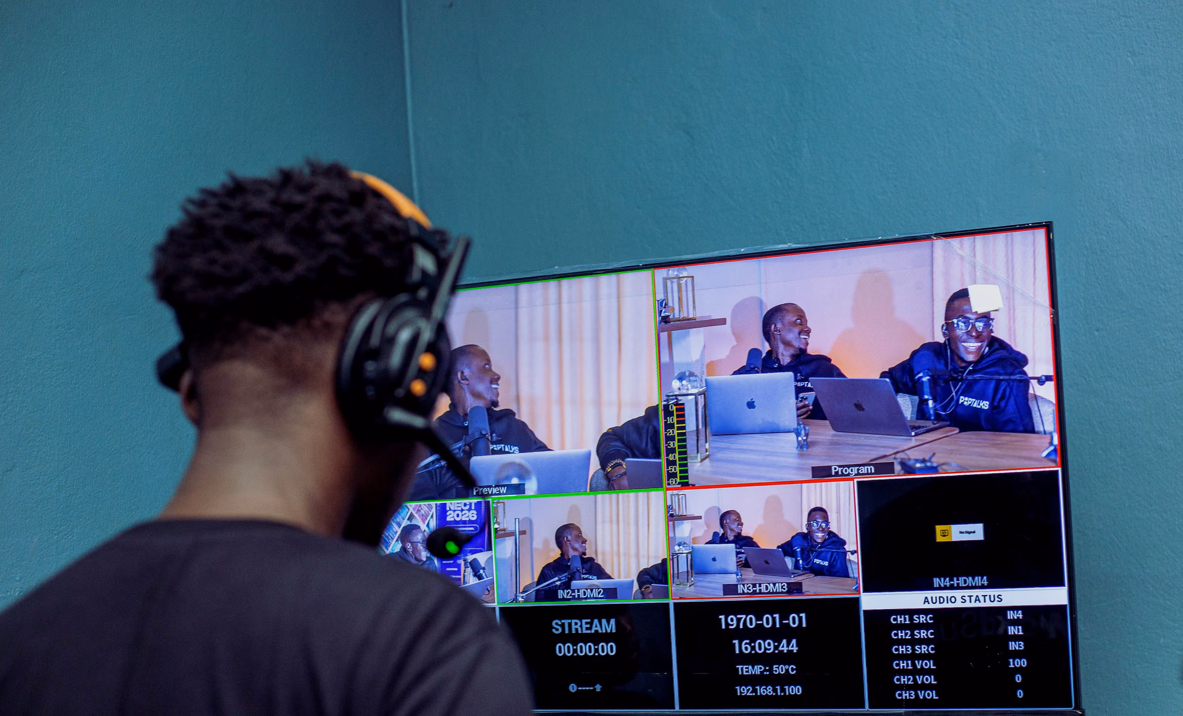 Operator in a headset facing a large multiview monitor of live camera feeds and stream status