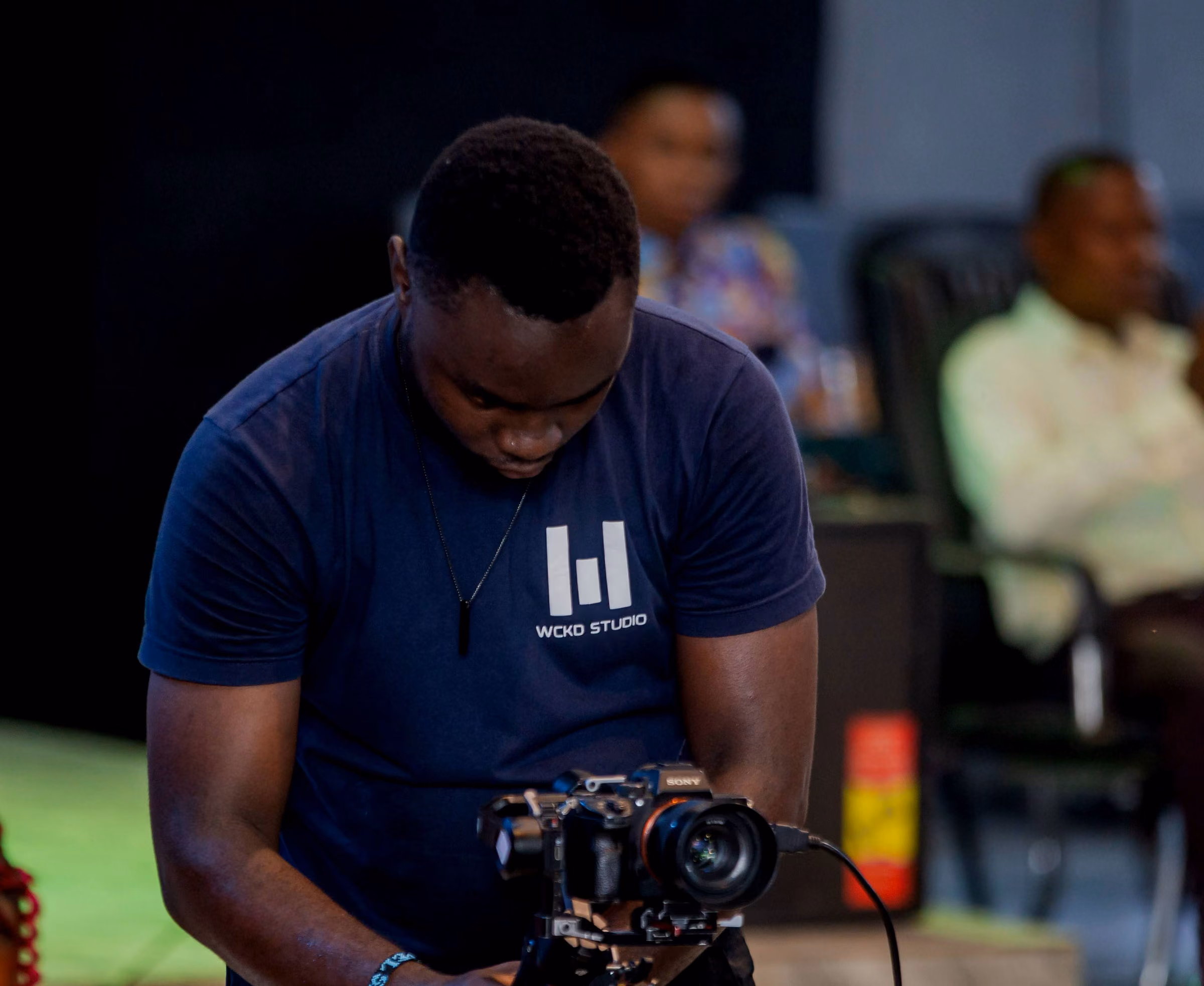 Operator in a WCKD tee looking down at a camera on stage level